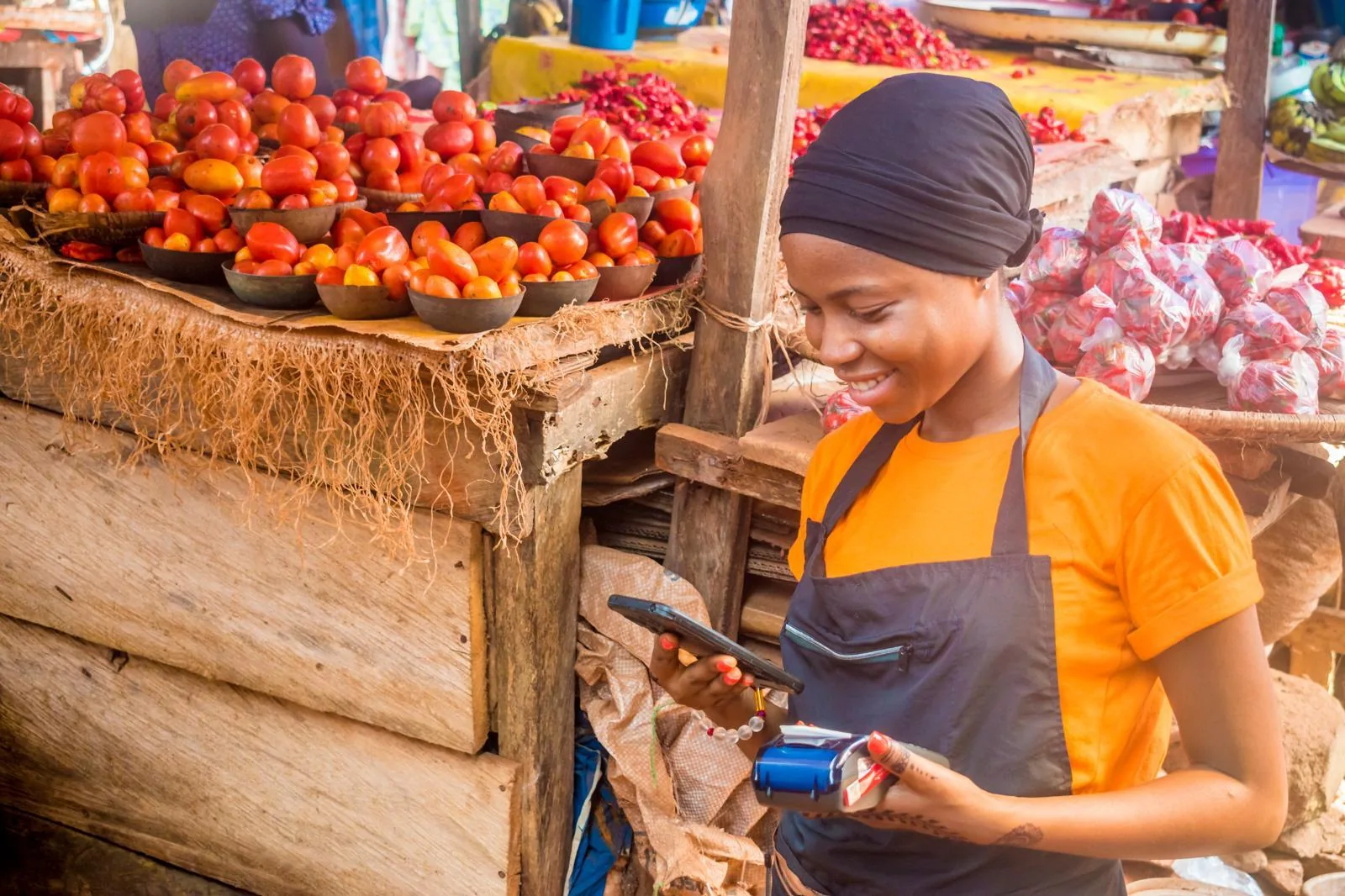 Commerçante utilisant un téléphone et un terminal de paiement sur un marché